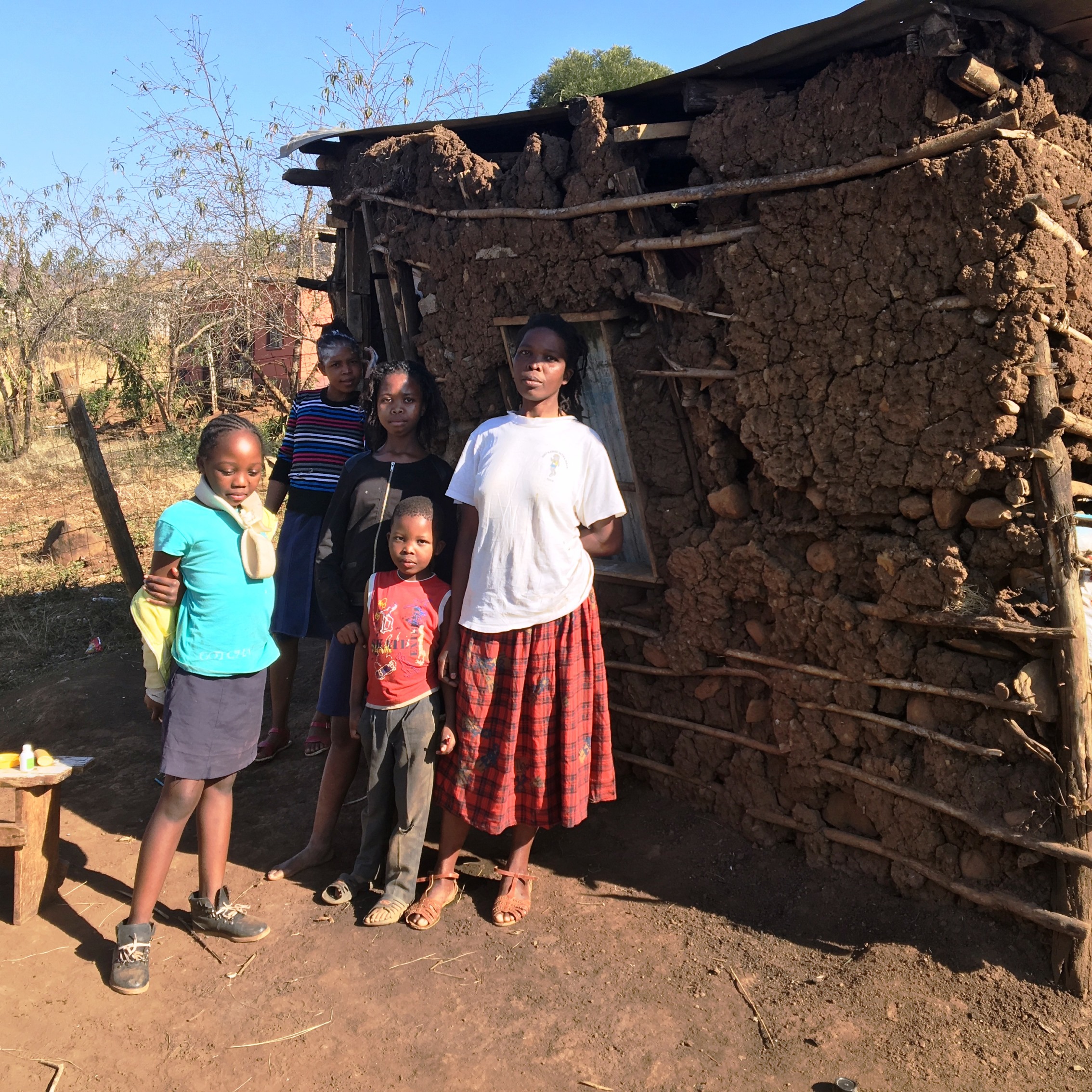 Photo of a family in front of a mud house