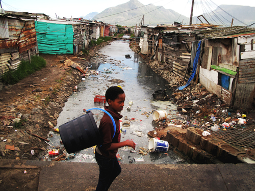 A child walks past a canal in Masiphumelele.