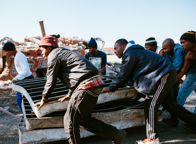 Residents work together to push a large piece of scrap metal from the demolition.